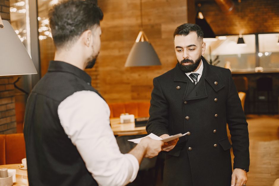 A waiter hands a menu to a customer in a stylish restaurant interior.
